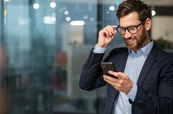 b2b-tech-odessa-news Man in a suit smiling and checking his mobile phone